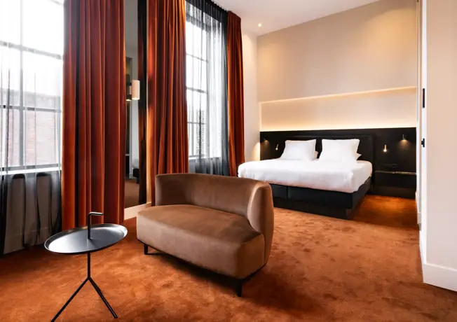 Schlafzimmer mit einem Bett, einer Bank und einem Tisch.