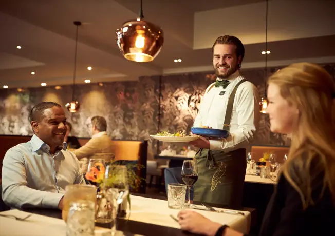 Ober serves dishes at restaurant De Valkenier.