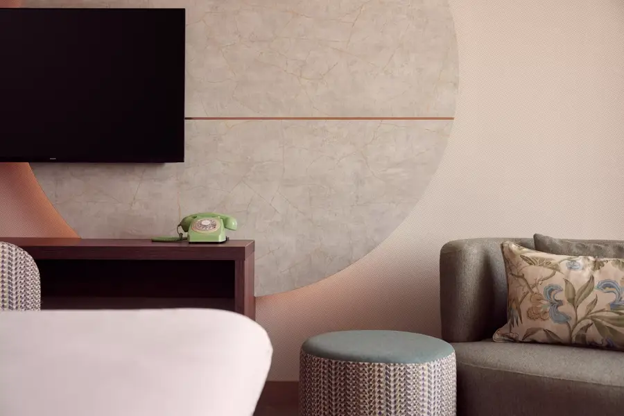 hoekje van de hotelkamer met tv en een bankje
