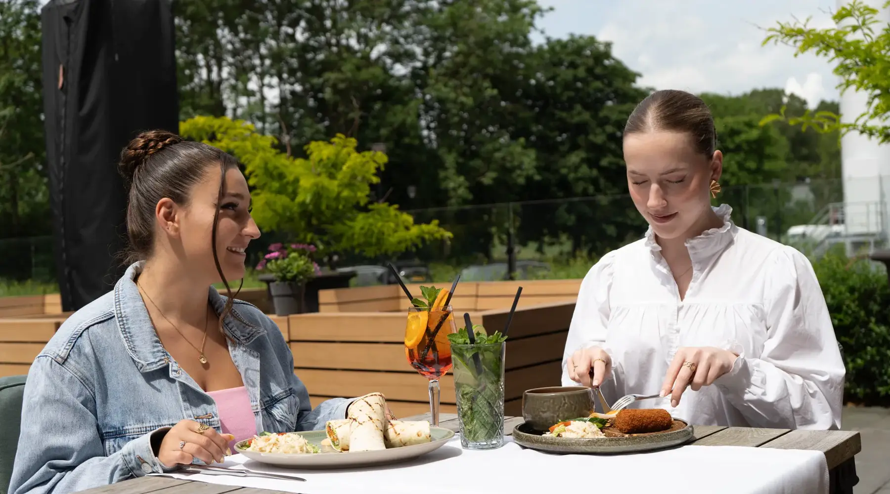 Twee vrouwen op het terras met lunch en cocktails.