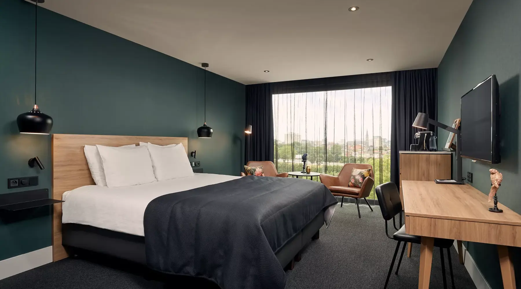 Kamer in hotel Antwerpen. bed met 2 stoelen aan klein tafeltje.1 stoel aan het bureau voor de TV. 