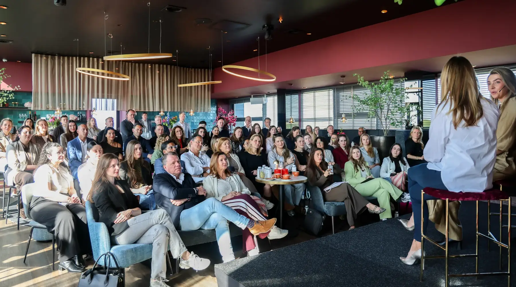 Een zaal vol met mensen luisteren naar 2 sprekers tijdens een B2B event.