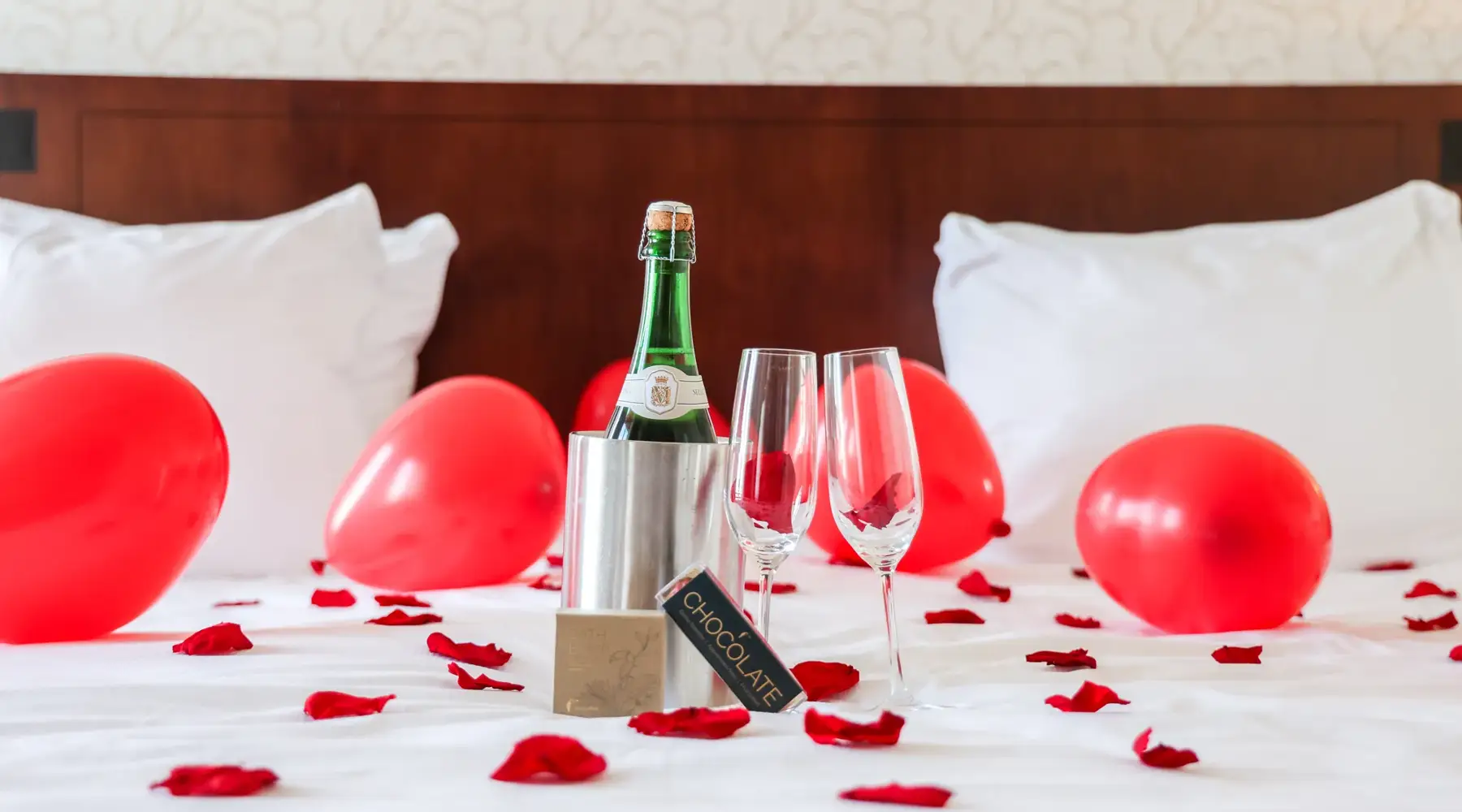 Kamerpakket met champagne, rozenblaadjes, champagnefles, ballonnen, bruisbal en chocola