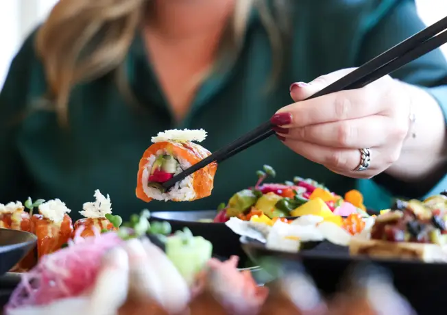Vrouw pakt sushi met stokjes