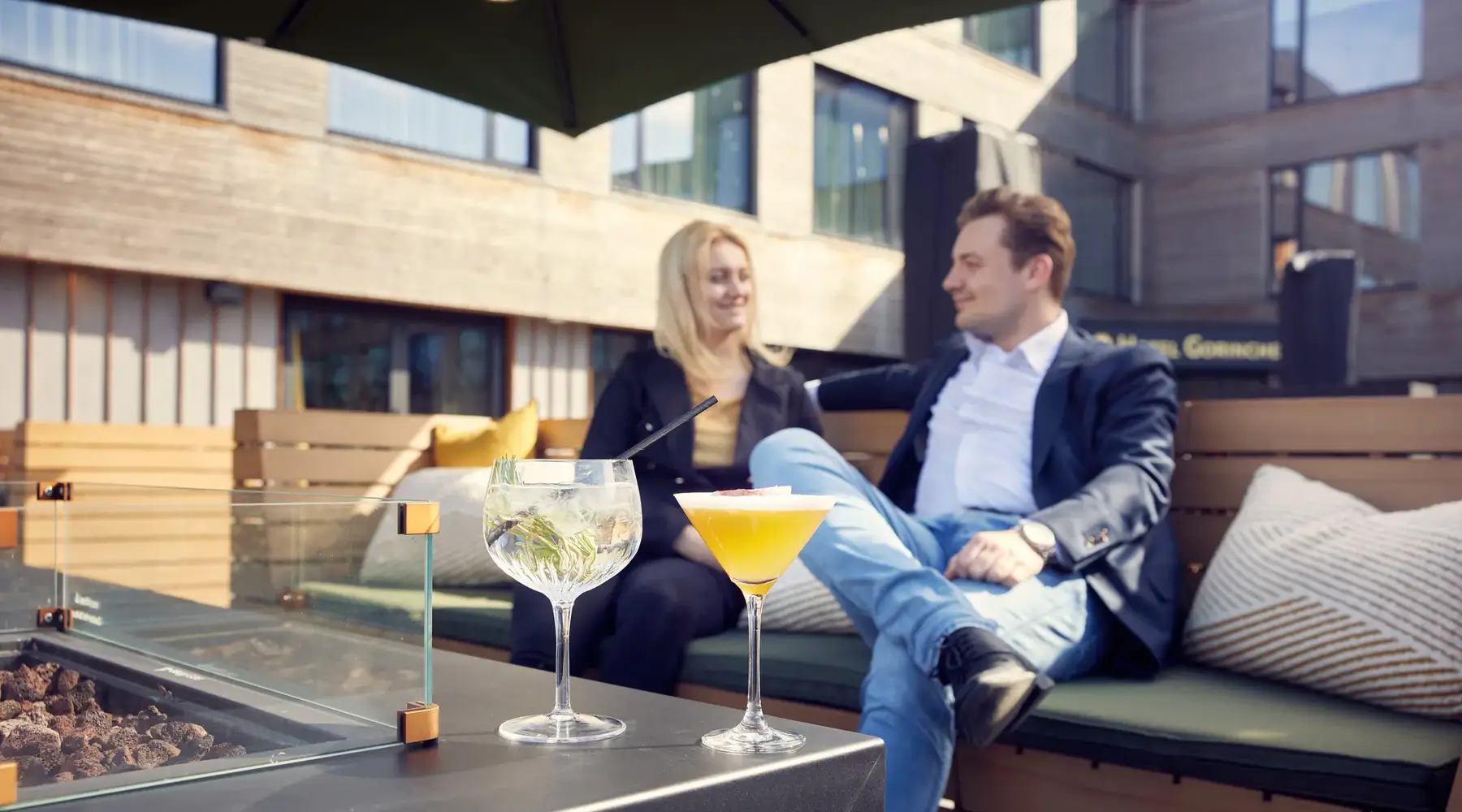 Vrouw en man buiten op het terras met twee cocktails op tafel.