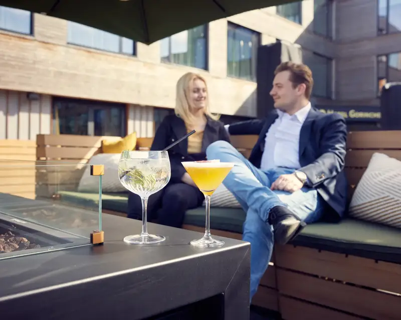 Vrouw en man buiten op het terras met twee cocktails op tafel.