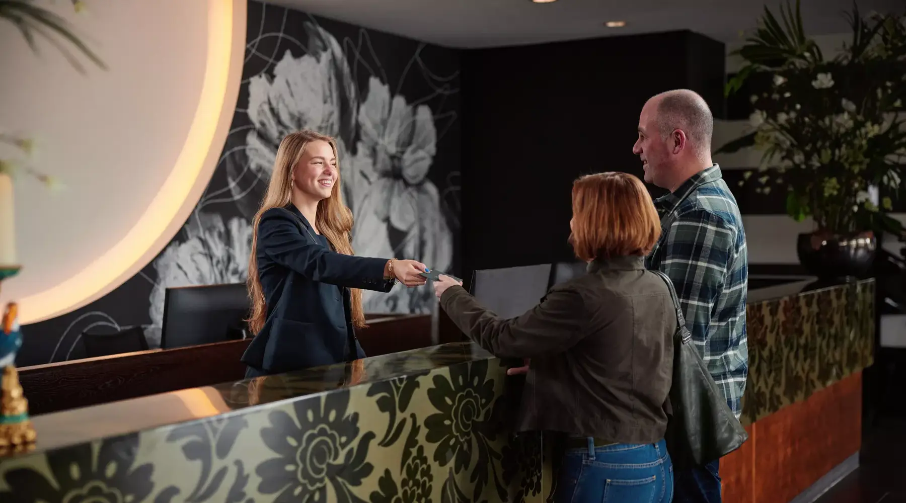 Receptioniste geeft de kamerpas aan gasten