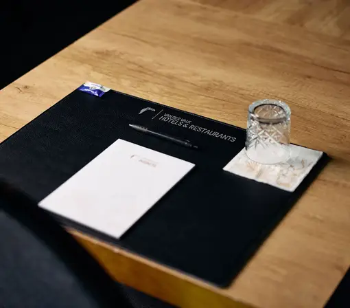 Table de réunion avec bloc-notes et verre d'eau, prête pour une réunion dans la salle de réunion Toekan.