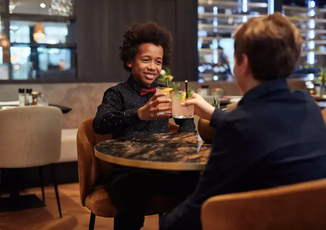 Twee kinderen die genieten van een drankje en een maaltijd in het restaurant van Van der Valk Nivelles-Sud met het Valk Kids menu.