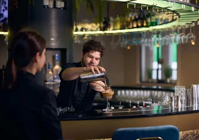 Barman die een cocktail aan het maken is aan de bar