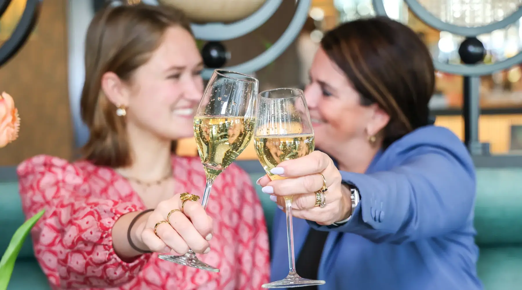Mère et fille trinquent avec du champagne à une table remplie de high tea.