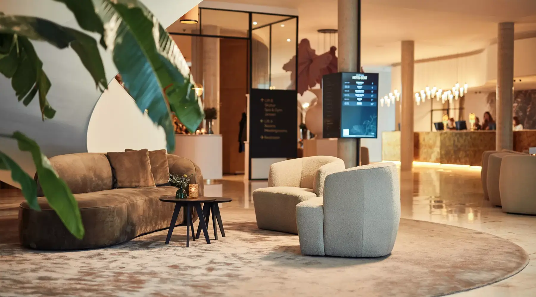 Moderne lobby van Van der Valk Hotel Gent met een grote plant en stijlvolle meubels.