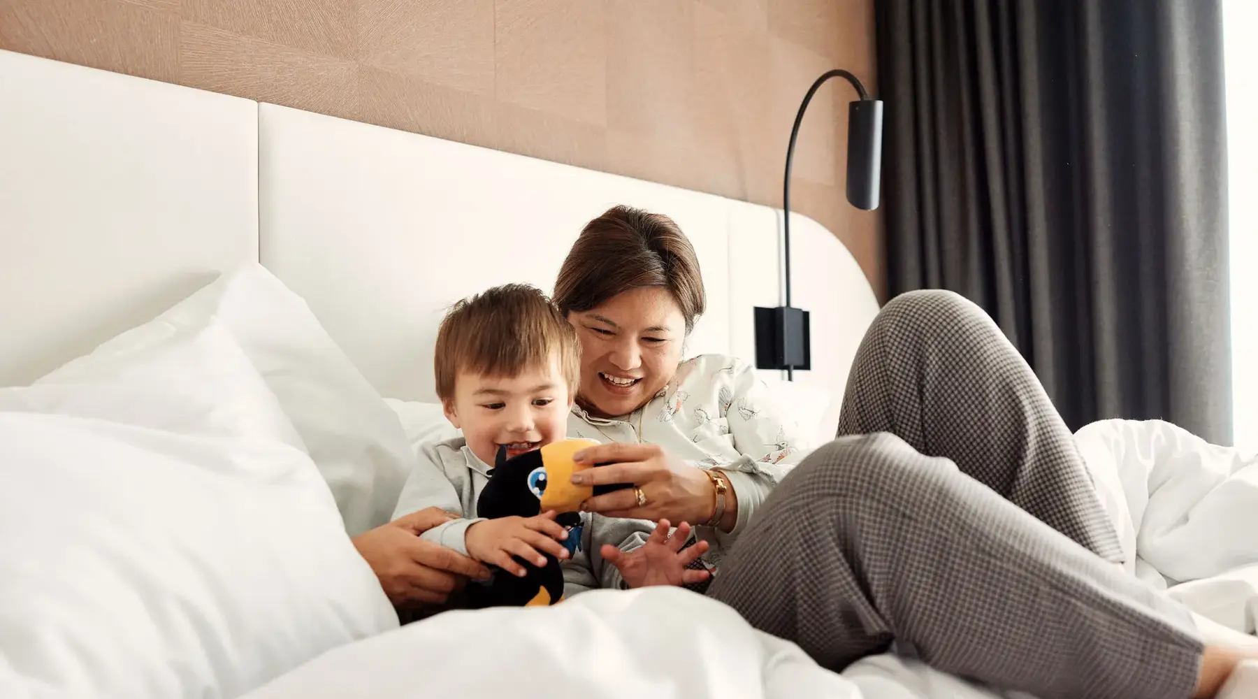Mutter mit Sohn im Bett mit Tukan Kuscheltier.