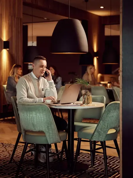 Mann arbeitet am Laptop im Hotelrestaurant