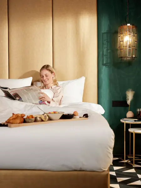 Vrouw geniet van de krant en ontbijt op bed