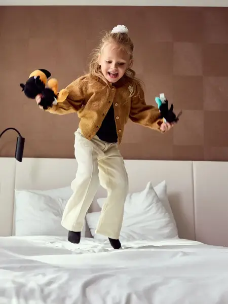 Girl jumps on hotel bed