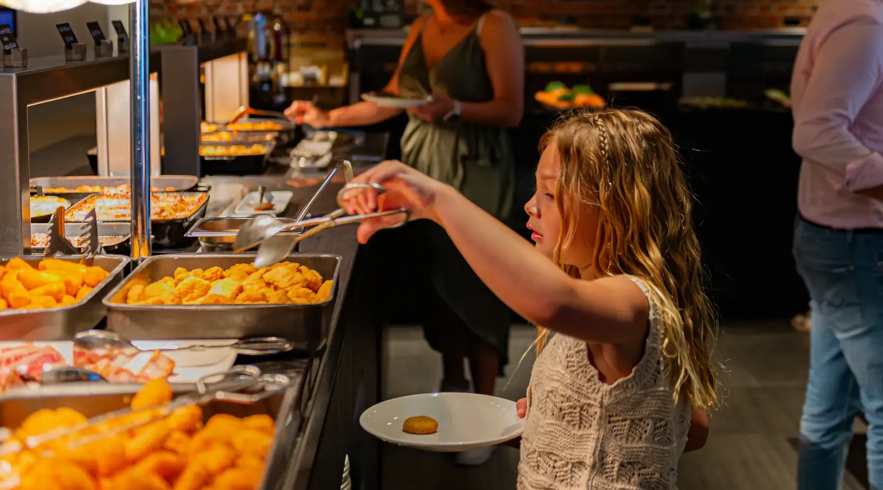 Meisje dat haar bord opschept aan het buffet.