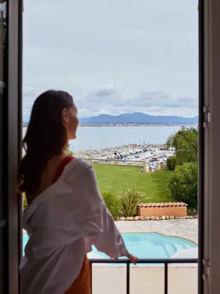 Vrouw kijkt vanaf haar accommodatie op een haven in de Côte d'Azur