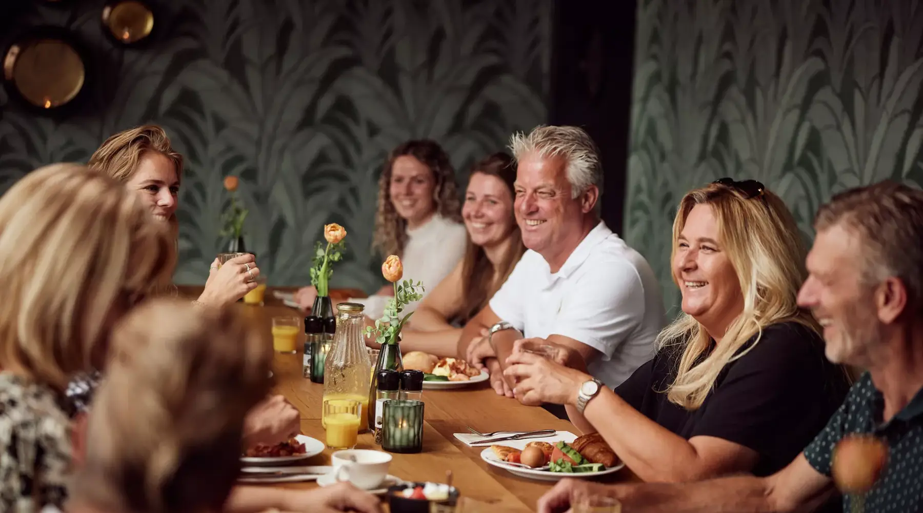 Gruppe von 10 Personen an einem langen Tisch mit Frühstück.