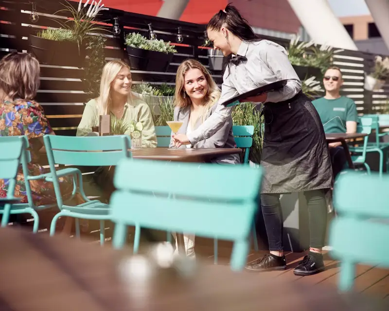 Twee vrouwen zitten op een terras en worden bediend