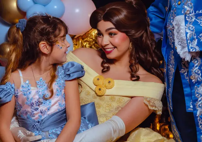 Prinzessin im gelben Ballkleid sitzt zusammen mit einem Mädchen im blauen Prinzessinnenkleid während eines Märchenfest.