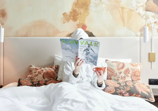 persoon in bed met koffie en valk magazine