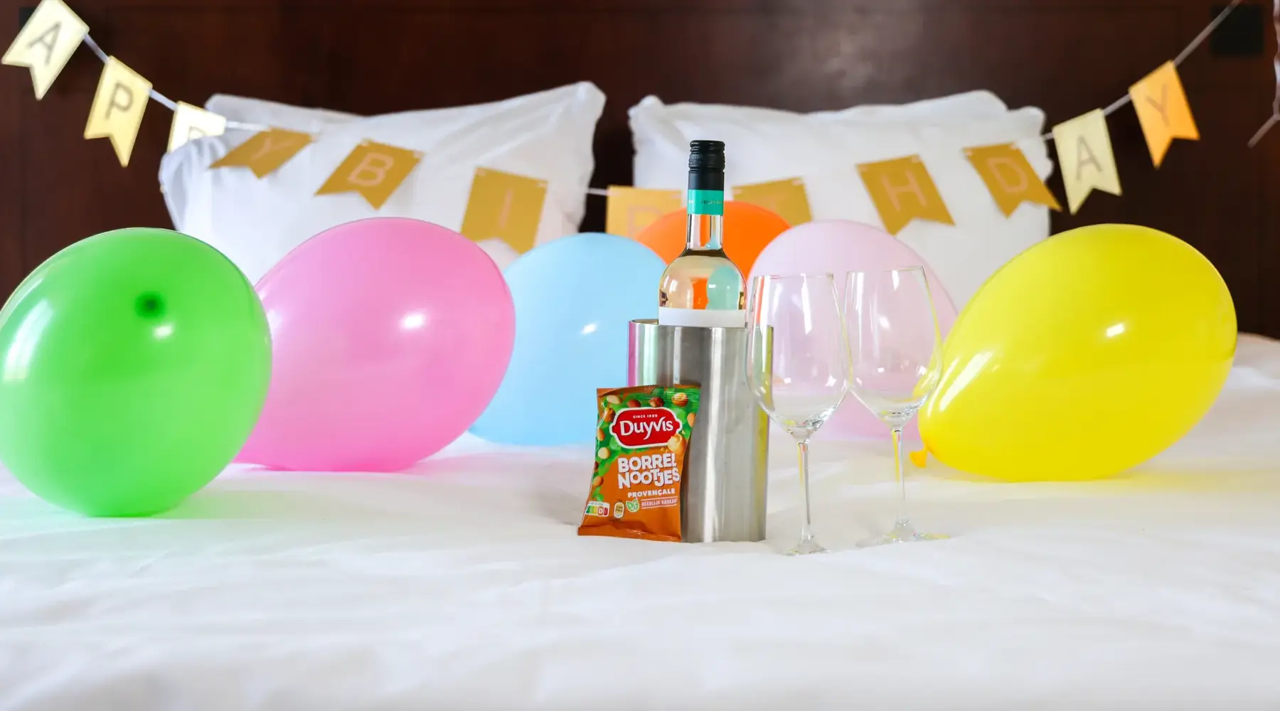 Verjaardagspakket met slingers, ballonnen, een fles wijn en borrelnootjes