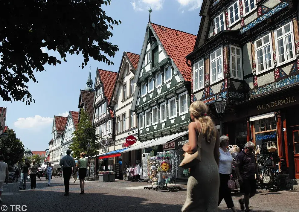 Lively old town street with traditional half-timbered houses and small shops. Visitors stroll through the street while cafes and stores shape the historical cityscape. The scene depicts the special atmosphere of historic towns in the region around Hildesheim.
