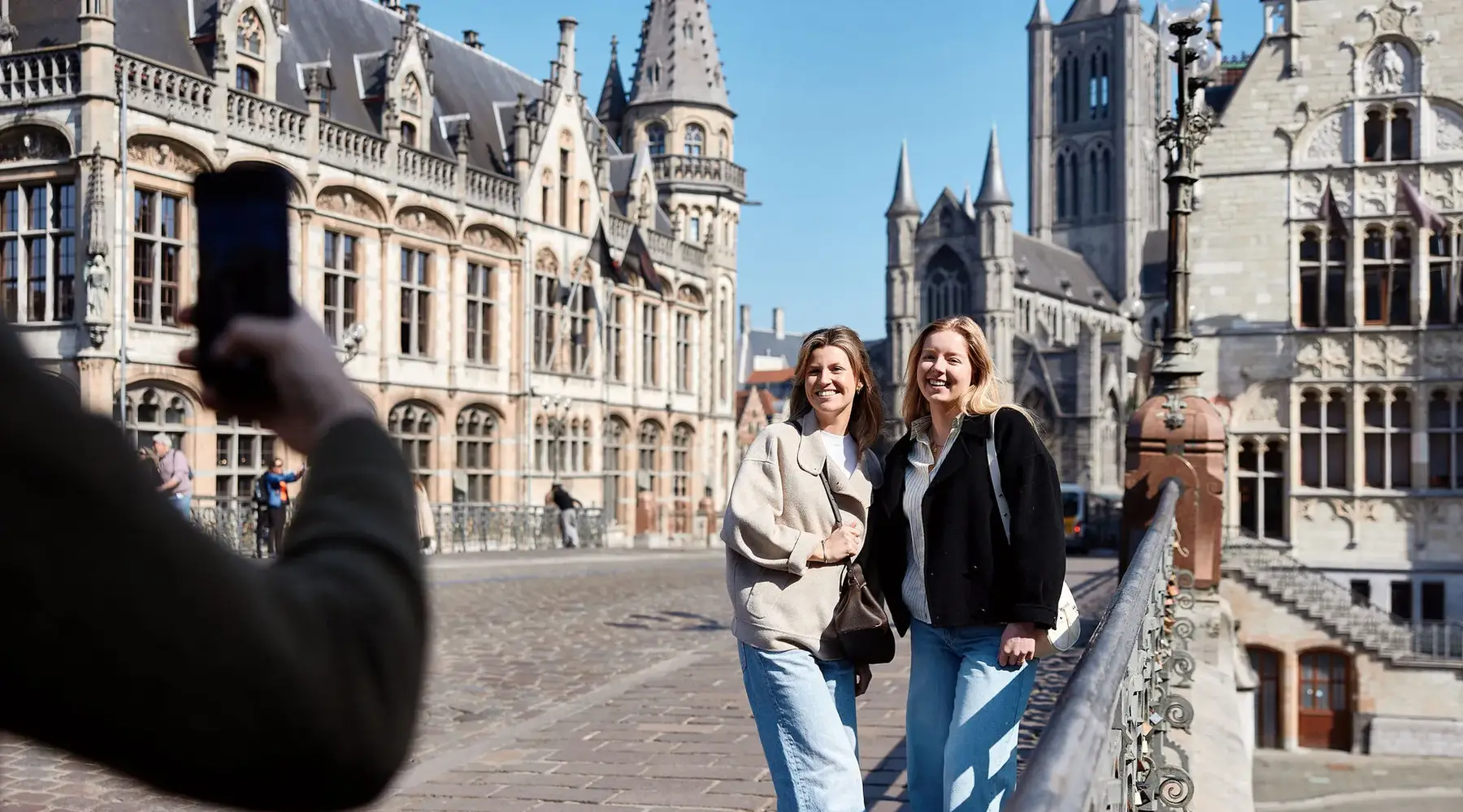 2 Freundinnen lassen ein Foto auf der Sint-Michielsbrug in Gent machen.
