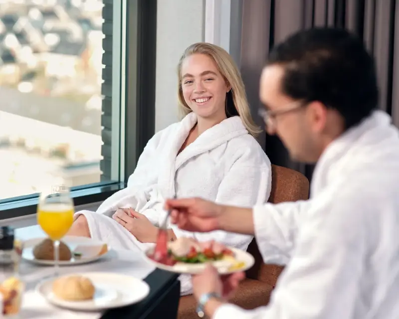 Frau frühstückt im Hotelzimmer