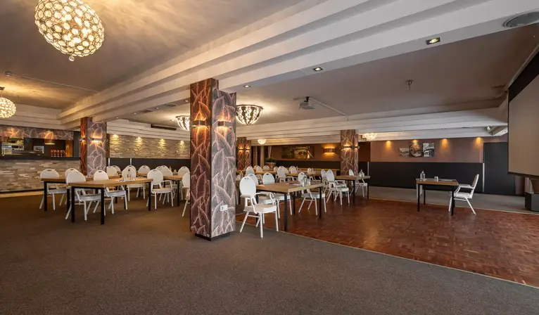 Überblick über den geräumigen Saal De Dieze im Cabaret-Stil mit Stimmungsbeleuchtung, verzierten Säulen und teilweise hölzernem Boden.