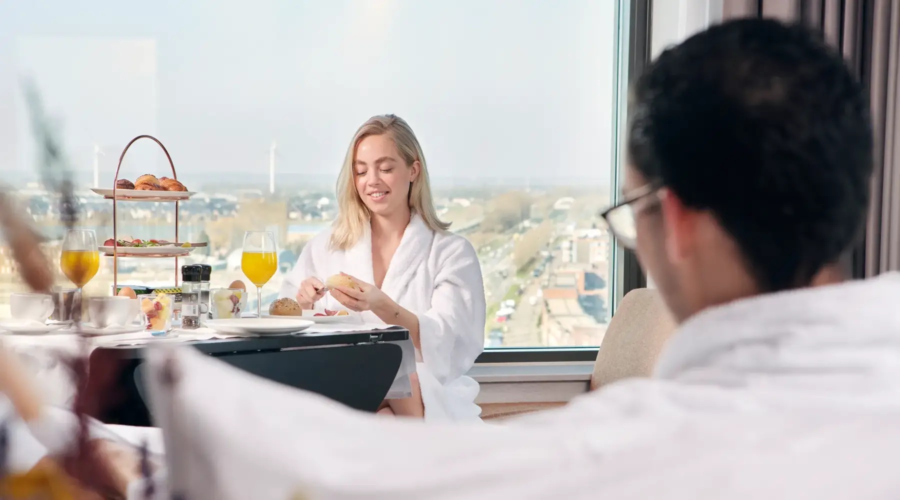 Vrouw eet ontbijt in hotelkamer