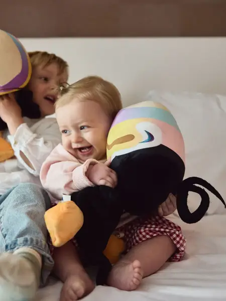 Kids die op bed spelen met toekan knuffel
