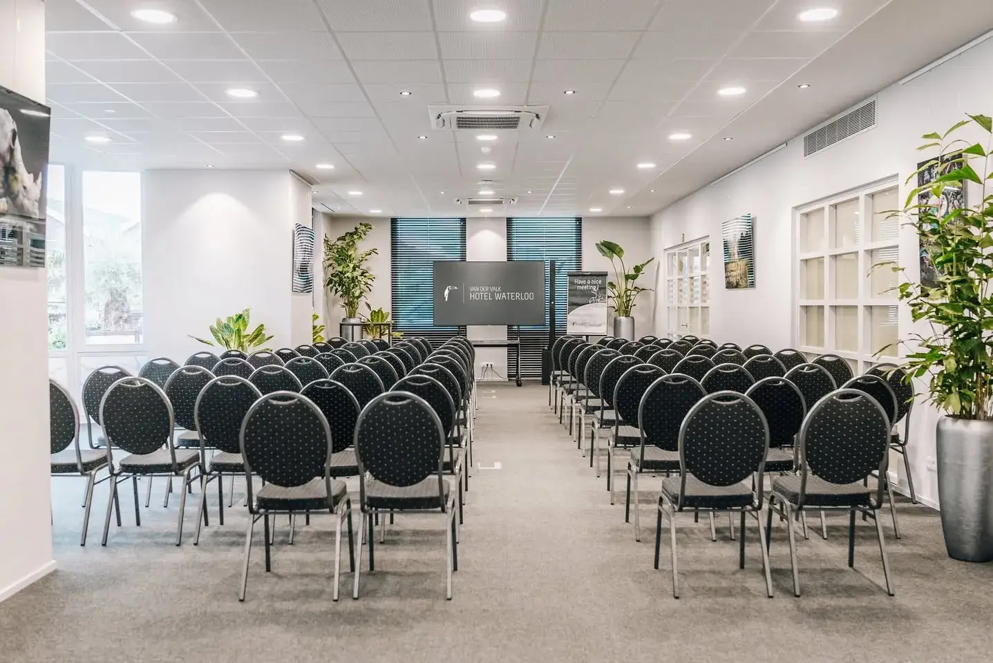 Large conference hall in theater setup with projection screen at Van der Valk Hotel Waterloo.