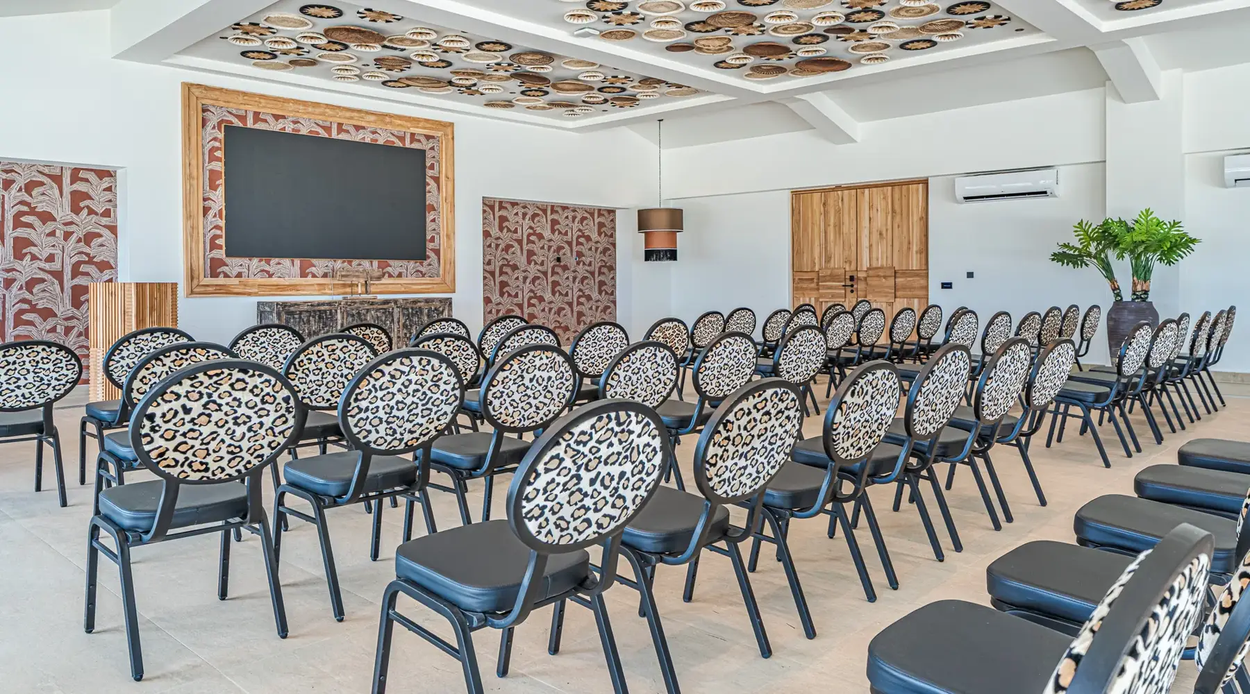 Saal im Hotel Bonaire. Stühle stehen in der Theateranordnung. Vorne hängt eine große Leinwand.