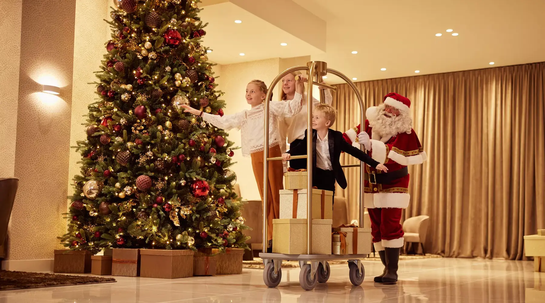 Kinder fahren zusammen mit dem Weihnachtsmann in einem Gepäckwagen in der Lobby