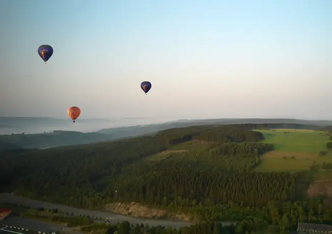 3 Heißluftballons über den grünen Hügeln Belgiens