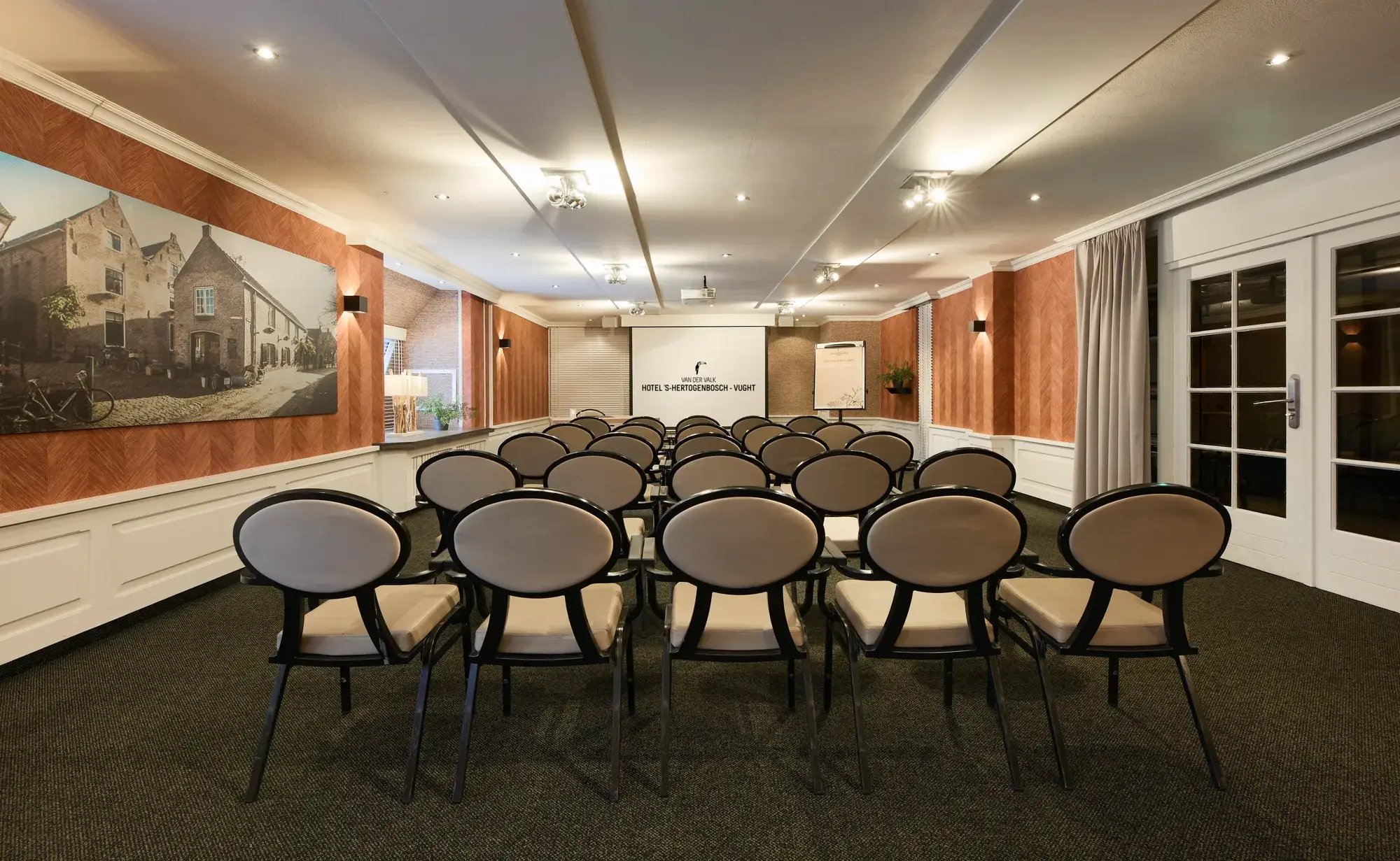 Vue d'ensemble de la configuration de la salle de spectacle De Uilenburg, face à l'écran de projection déroulé pour les présentations.
