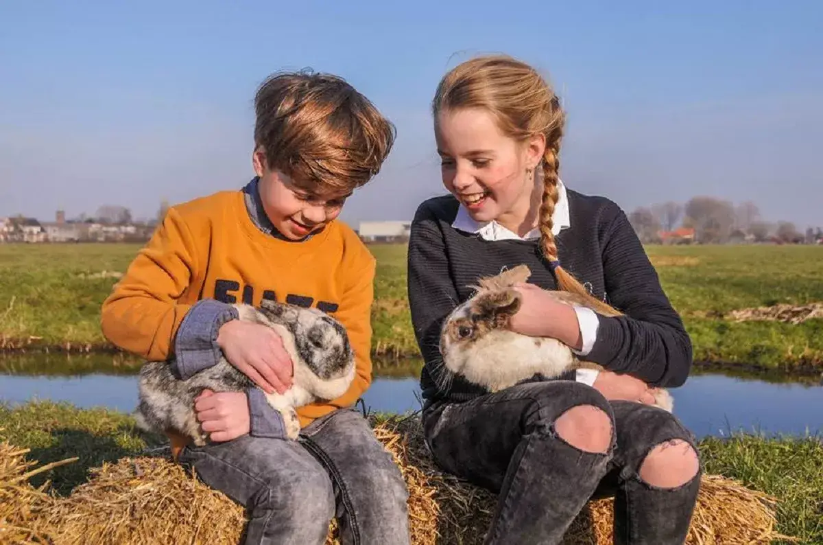 2 kinderen knuffelen met boerderijdieren