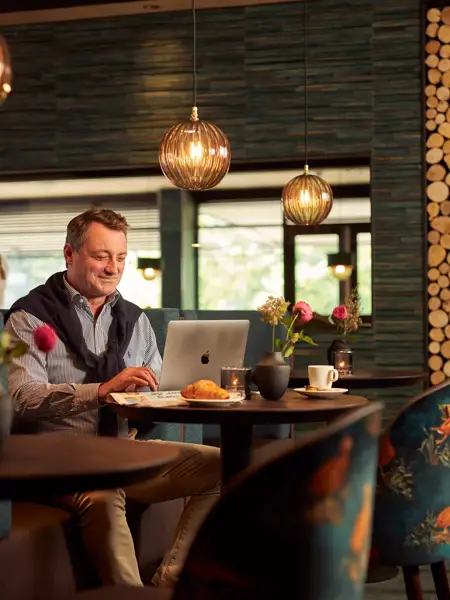 Ein Mann arbeitet in einem Hotelrestaurant an seinem Laptop