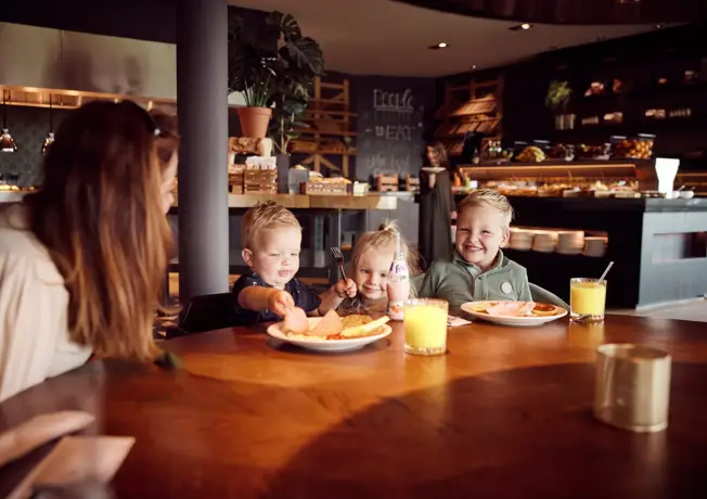 Kinderen genieten van ontbijt aan tafel in restaurant