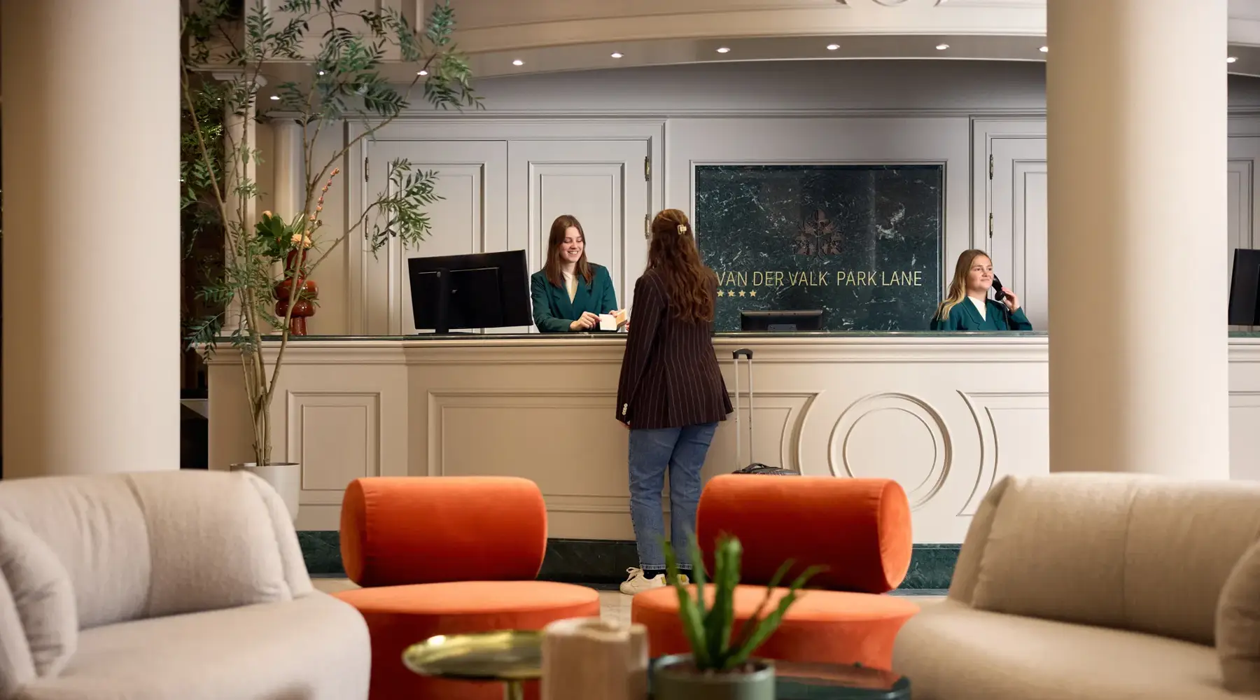 Vrouw aan de receptie bij Hotel Park Lane. Geholpen door dame met bruin haar.