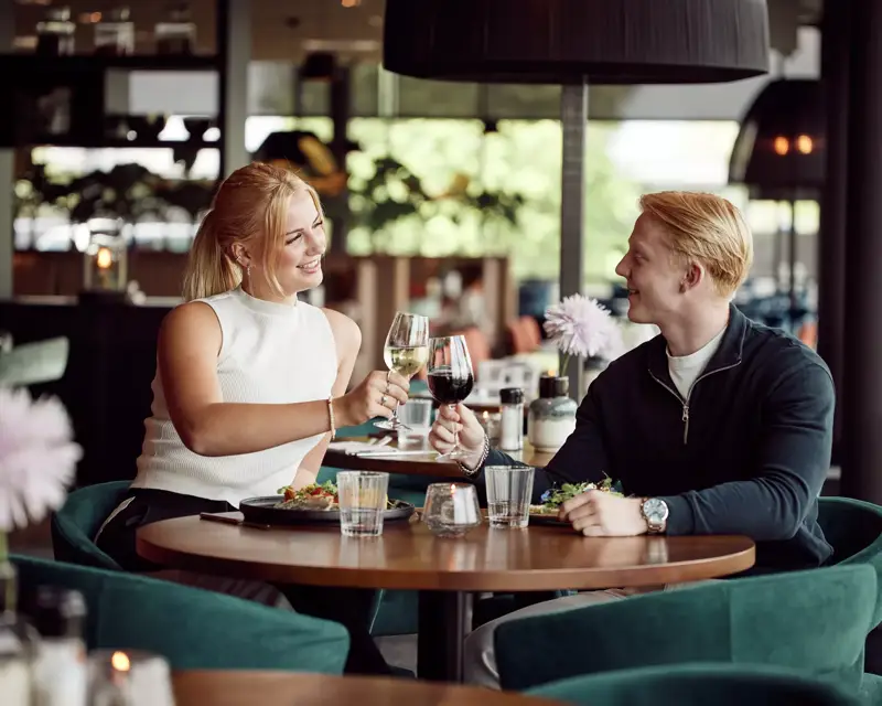 In love couple has dinner at a restaurant. They toast together. 