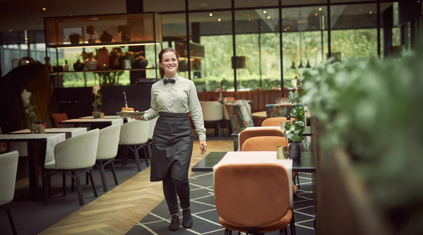 Ein Mitarbeiter bringt einem Gast im Restaurant ein Gericht.