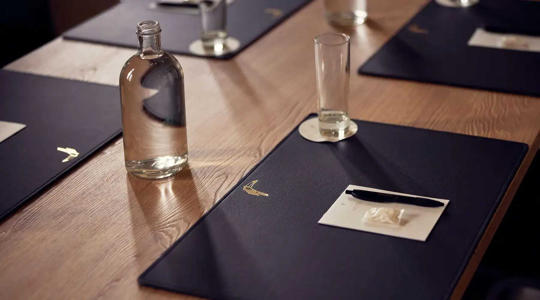Detail photo of a meeting table with notepad, notebook, and pen