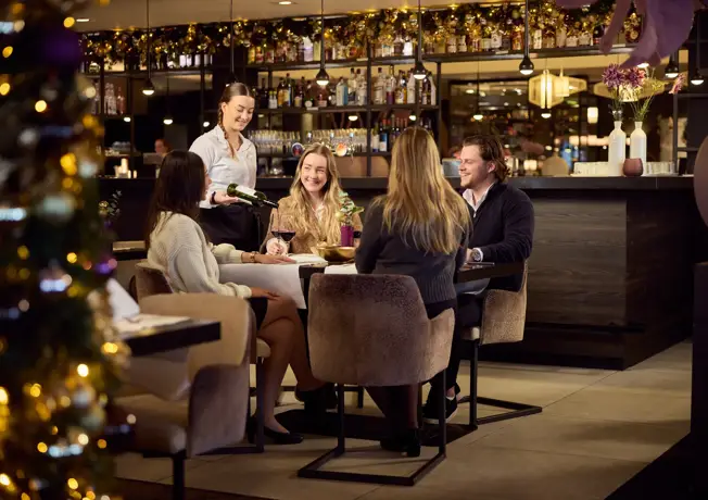 Foto van 4 personen die gezellig in een restaurant met kerstversiering zitten