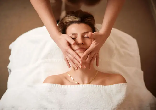 Une femme reçoit un massage du visage au Weleda City Spa à l'Hôtel Gent.