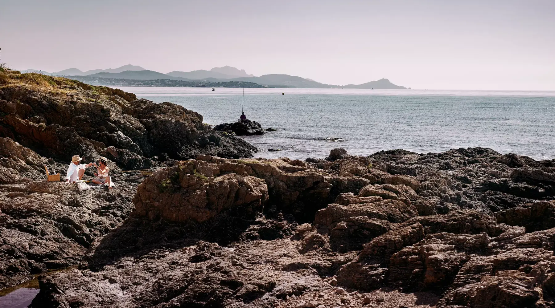 A couple enjoys local products during a picnic by the sea.