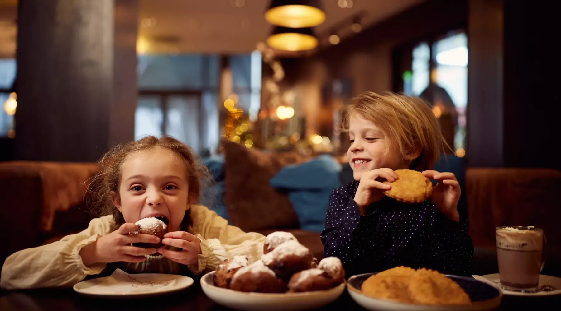 Kinderen eten oliebollen en appelflappen.