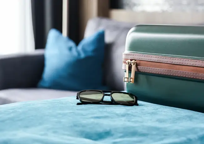 Koffer mit Sonnenbrille auf Bett 